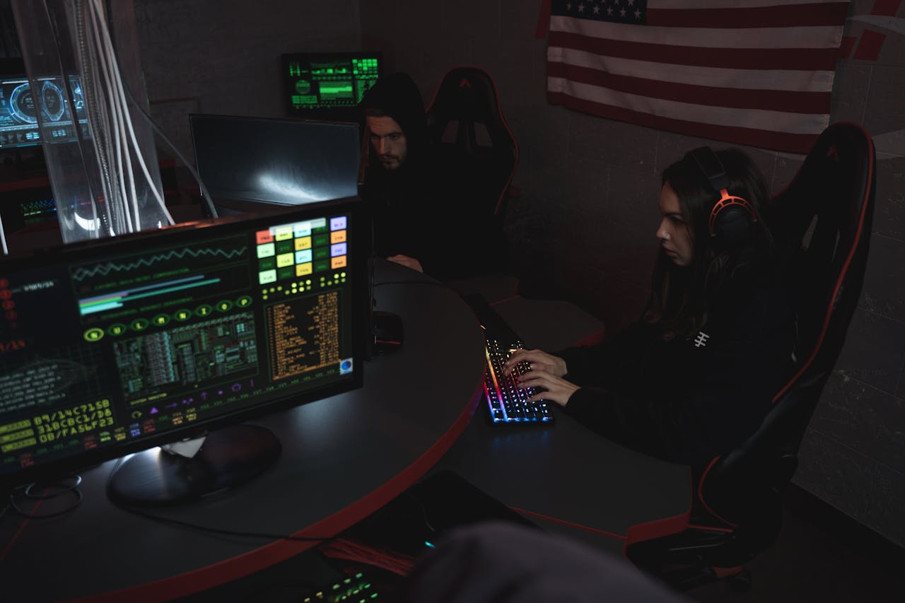 About Cybersecurity professionals working on computer systems, focusing on data protection in a dimly lit room.