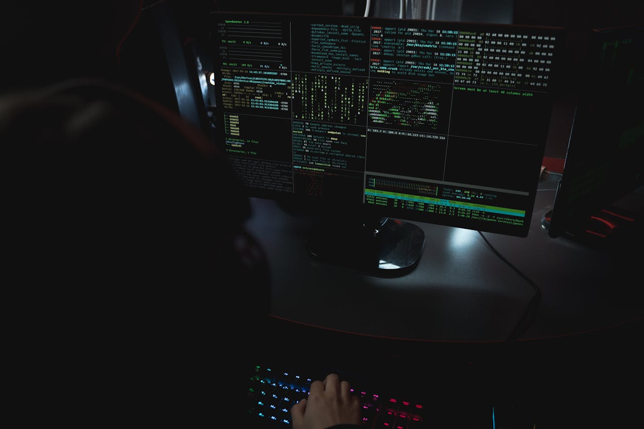 Home Dark room setup with code displayed on PC monitors highlighting cybersecurity themes.
